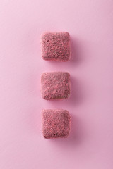 Top view of handmade chocolate truffles in raspberry powder on colored pink background