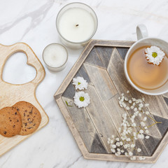 flat lay with breakfast black tea on wooden desk with flowers, sunglasses and cookies on marble background