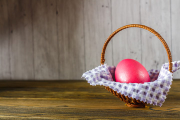 Easter egg in the basket. Wooden background, place for your text.