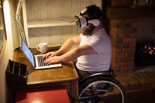 Disabled man in virtual reality headset using laptop