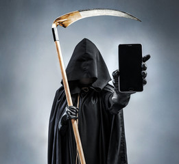Image of Grim Reaper holding and showing black mobile phone with blank black screen. Photo of...