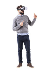 Smart casual businessman wearing vr glasses pointing finger up at copyspace. Full body isolated on white background. 