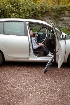 Disabled man holding wheelchair while boarding in his car