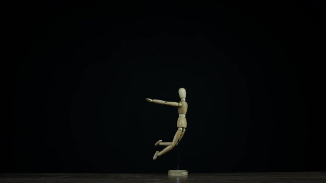 Stopmotion falling wooden figure dummy in studio on black background rotating