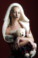 Christmas concept - beautiful woman in Santa Claus costume holding Teddy bear. Santa helper with Christmas present in hands.