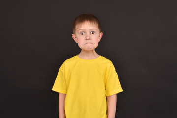Emotional guy. Portrait of a boy in a T-shirt. Shooting in the studio. A young man on a black background.