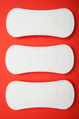Obraz premium Three female pads on a red background, vertically.