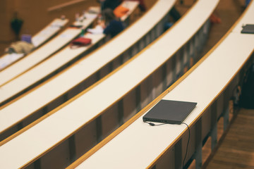 Black notebook laptop computer on the desk in university auditorium