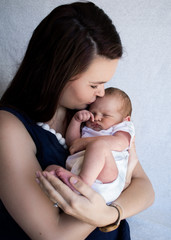 Fototapeta na wymiar Mother holding sleeping newborn baby kissing his forehead