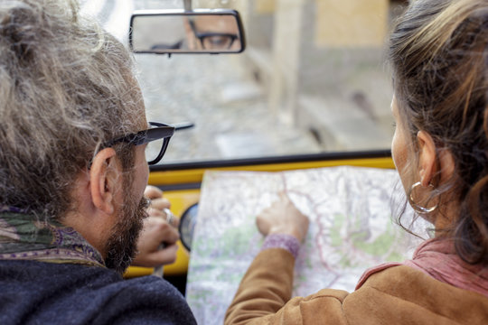 Woman and man talking looking at map. Back view. Caucasian couple in love roadtrip vacation italian travel on convertible car