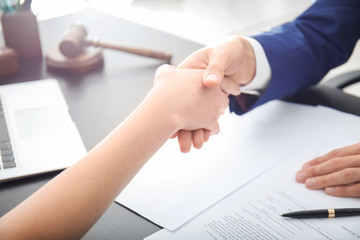 Lawyer shaking hands with client in office, closeup