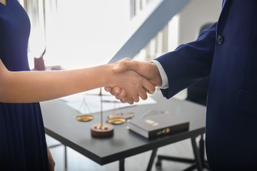 Lawyer shaking hands with client in office, closeup
