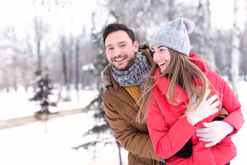 Fototapeta premium Young couple in snowy park on winter vacation
