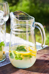 Lemonade in the jug with mint on the table outdoor