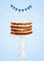 Layer cake with blue flags on white stand on isolated blue background