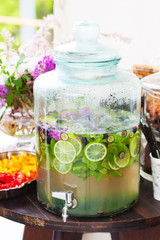 Table at a party with lemonade and flowers on a bright background