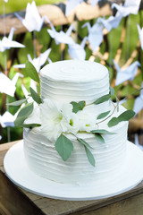 Wedding white cake decorated with flowers and eucalyptus on stand on green background