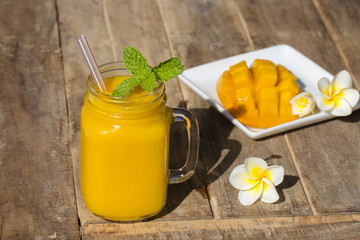 Fresh organic mango shake in glass mug on wooden table, close up