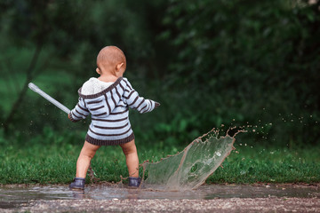 Little boy playing in puddle in spring forest on the Music of Summer festival, july 2017, Podolsk,...
