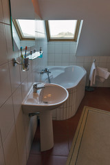 Modern bathroom with corner bath, washbasin and window.