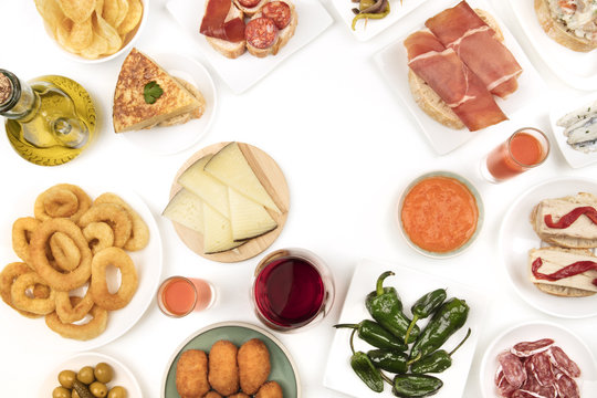 An overhead photo of Spanish tapas, forming frame on white with copy space