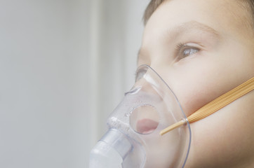 A little boy with a nebulizer mask on his face, medical inhalation treatment.
