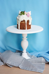 Easter cake decorated with candied fruit on white stand on blue background