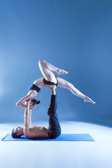 Young couple practicing acro yoga on mat in studio together. Acroyoga. Couple yoga. Partner yoga.