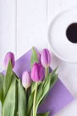 Black coffee in a white cup, pink tulips and book on a white background. Top view, free space, flat lay