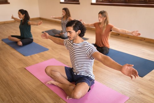 Group Of People Performing Yoga Exercise In Fitness Club