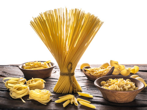 Different pasta types on wooden table. White background.