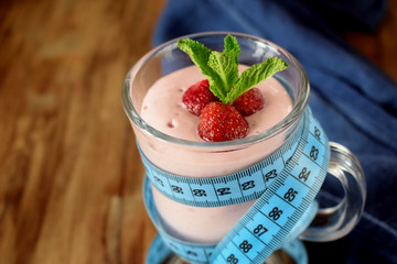 Strawberry protein cocktail decorated with berries and mint in an Irish mug wrapped into a blue measure tape