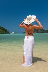  lady in black beachwear, floppy hat, sunglasses enjoying sun on tropical destination during summer...