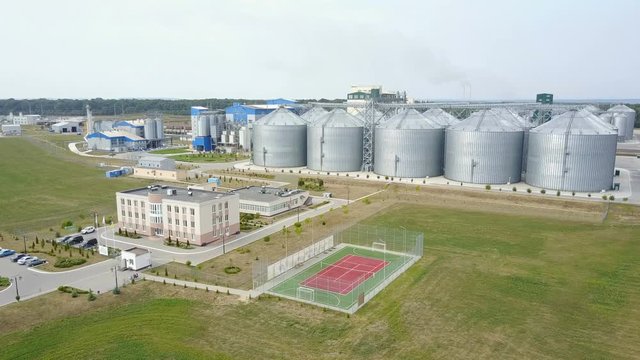 Aerial view of grain elevators surrounded by green fields.