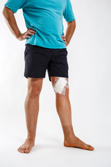 Young man with elastic bandage on knee, on a white background. Man on crutches, after the operation