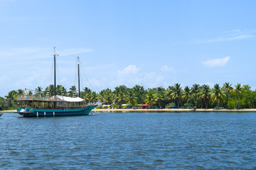 Excursion boat is waiting for the tourists in front of a beautiful tropical island with white...