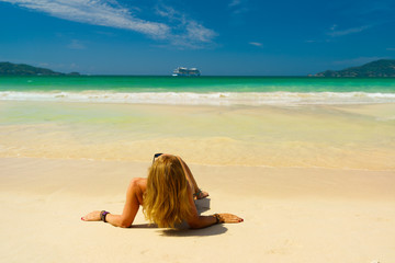 Fototapeta na wymiar Cute woman relaxing on the summer beach. Happy lifestyle. White sand, blue sky and crystal sea of tropical beach. Vacation at Paradise. Ocean beach relax, travel to islands