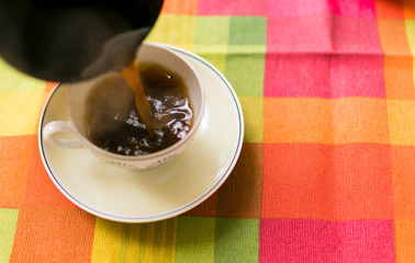Pouring coffee into the cup.