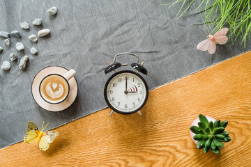 Switch to summer time on alarm clock with wooden background from above