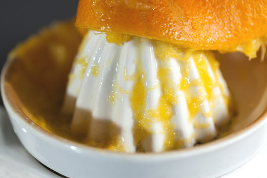 Naranja exprimi&eacute;ndose en un exprimidor blanco
