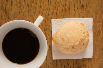 Pao de Queijo is a cheese bread ball from Brazil. Also known as Chipa, Pandebono and Pan de Yuca. Snack and espresso coffee on rustic wood, flat design.