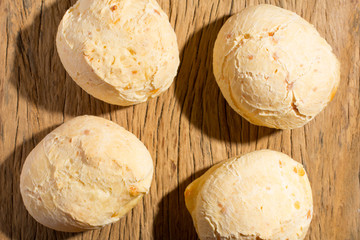Pao de Queijo is a cheese bread ball from Brazil. Also known as Chipa, Pandebono and Pan de Yuca. Group of snacks on rustic wood, flat lay design.