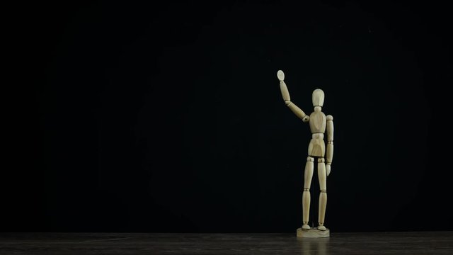 Stopmotion wooden figure dummy in studio on black background