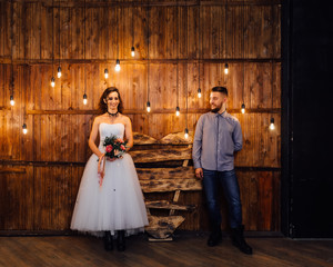 Wedding in the style of rock. Rocker or Biker wedding. Guys with stylish leather jackets. It's a rock'n'roll baby. Sweet couple in a photo studio. Steep shooting in a wooden location. Around the bulb