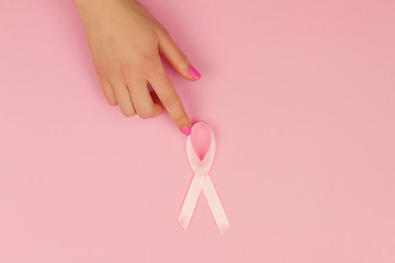 Woman's hand with pink tape as symbol of women illness mammary cancer isolated on pink background