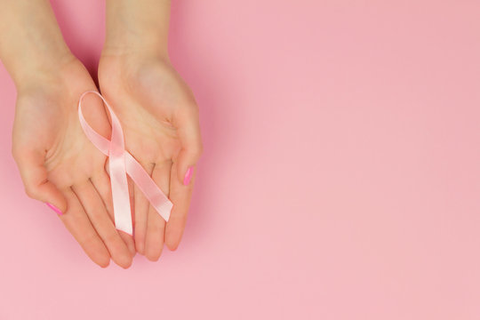 Woman hand with pink tape as symbol of women illness mammary cancer isolated on pink background