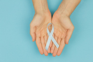 Man hands with cyan / blue tape as symbol of men's illness prostate cancer on cyan blue background