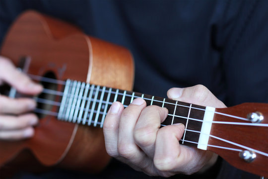 close up ukulele fretboard in musician hands