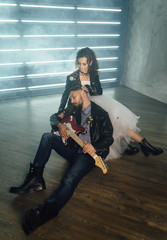 Wedding in the style of rock. Rocker or Biker wedding. Guys with stylish leather jackets. It's a rock'n'roll baby. Sweet couple in a photo studio. Steep shooting with electric guitar and smoke.