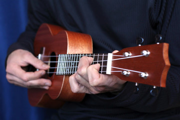 Fototapeta premium musician plays on ukulele, small depth of field
